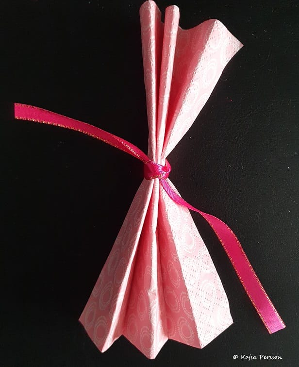 Knyt en rosett mitt på servetten med ett fint sidenband