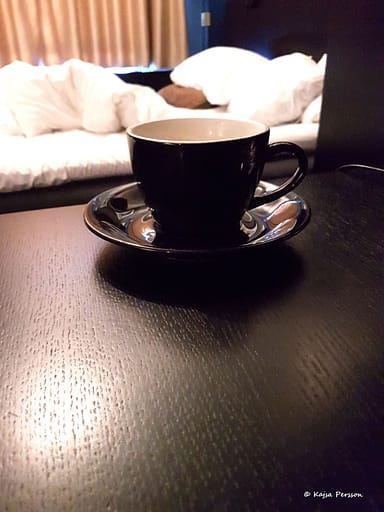 Kaffekopp framför en obäddad säng