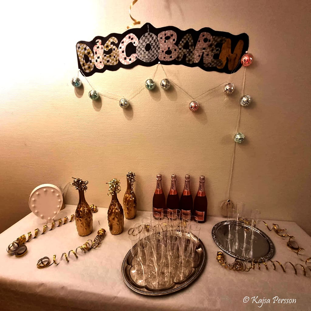 Välkomst bord med champagneglas på silverfat, bubbel, dekorationer, skylt ovanför med orden discobaren